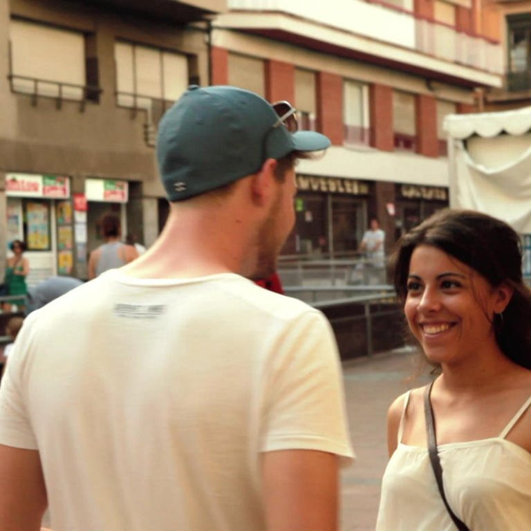 Ein junger Mann und eine junge Frau unterhalten sich auf der Straße.